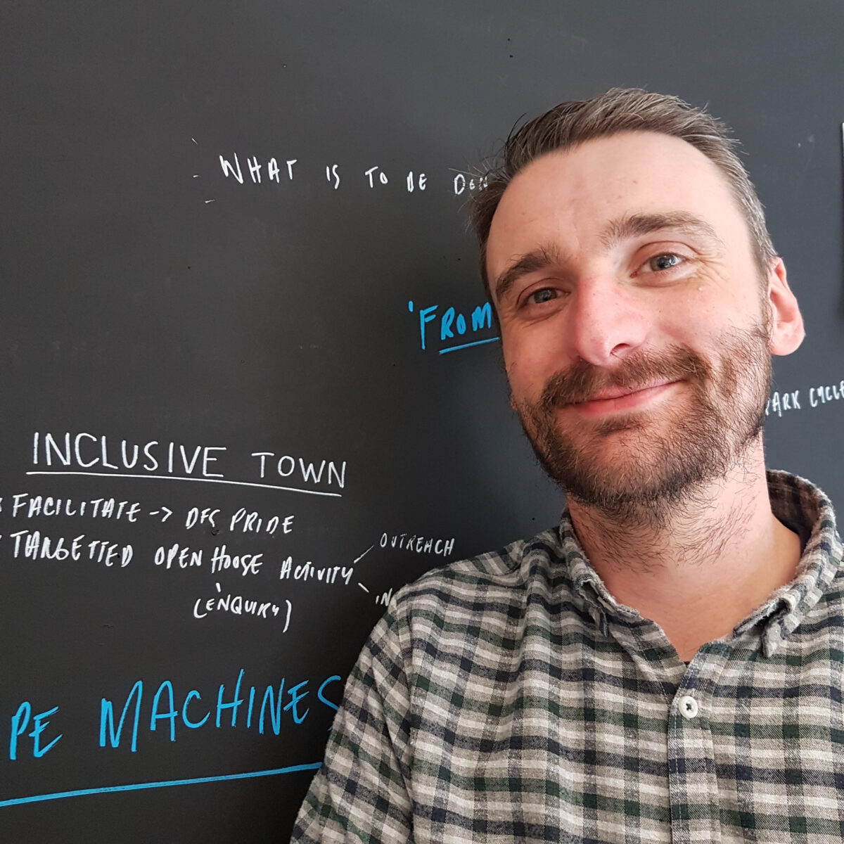 Martin O'Neill from the Stove network standing in front of the brainstorming blackboard in his office