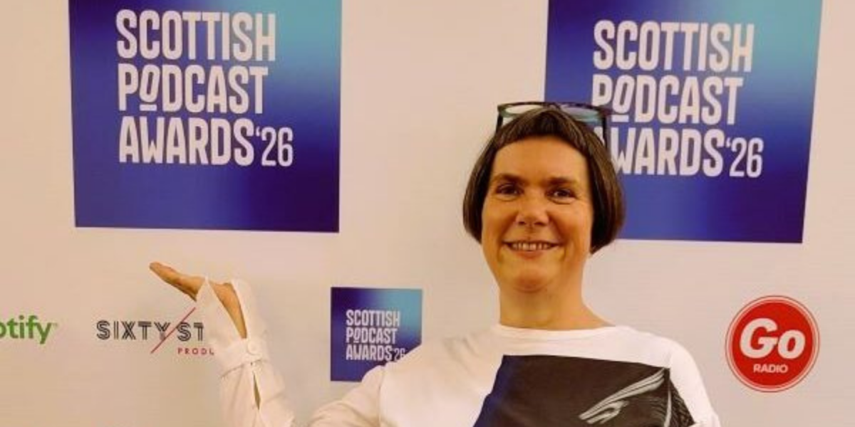 Kaska Hempel standing at the red carpet for the Scottish Podcast Awards 2026 wearing a great monochrome top and smiling